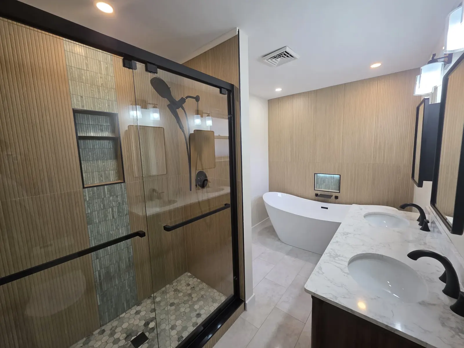 Double vanity with a white marble-look top, dark cabinets and a freestanding tub