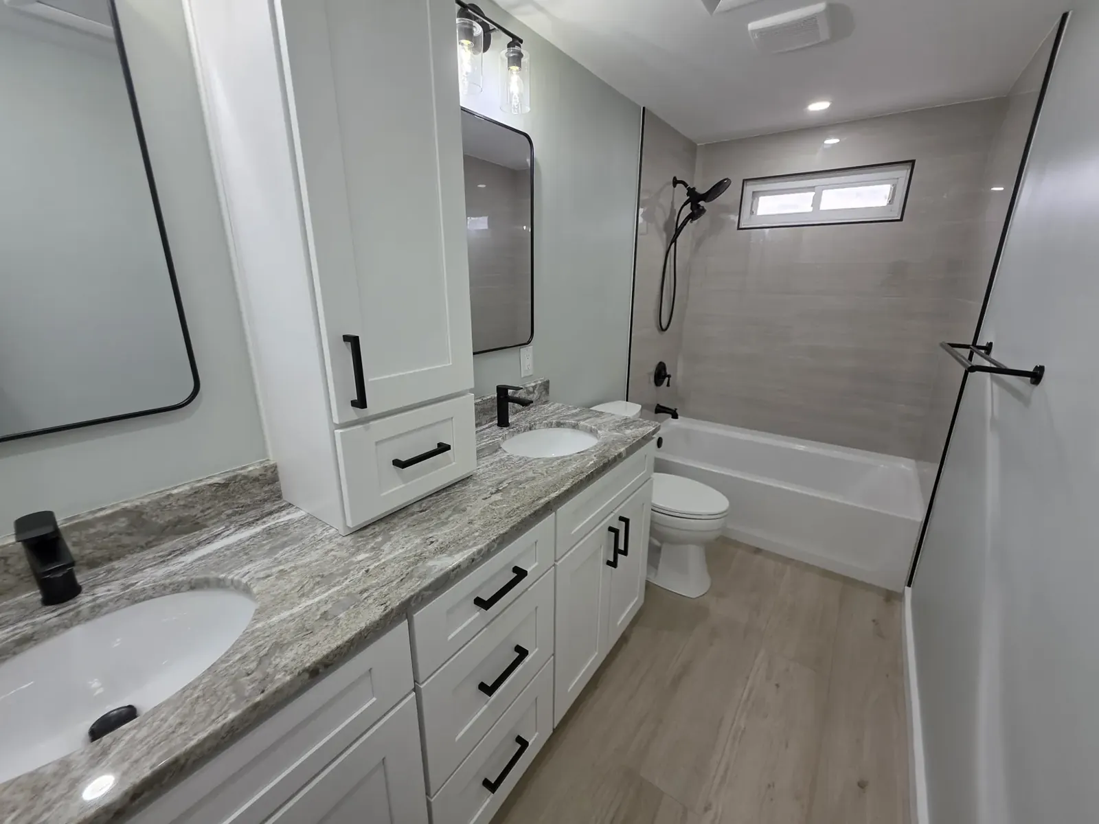 White shaker vanity with a granite top and a tall linen cabinet
