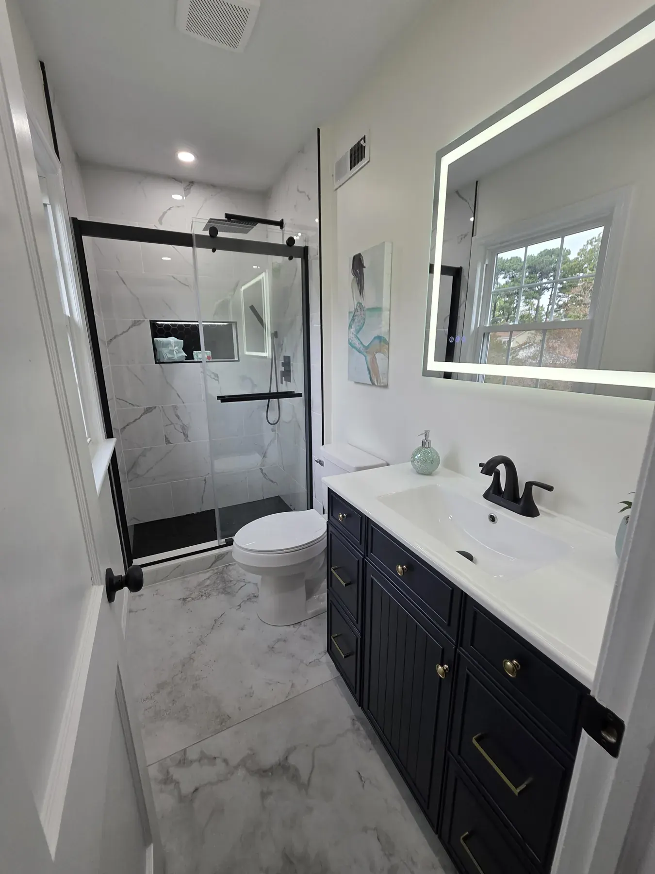 Navy shaker bathroom vanity with a white stone top and black faucet