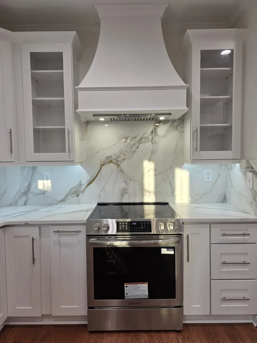 Full-height marble-look stone backsplash behind a range, with a white hood