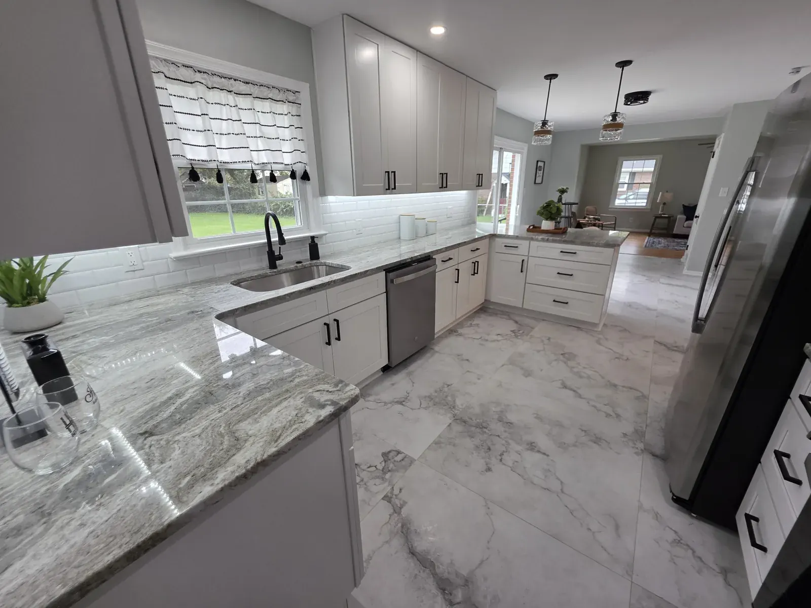 White shaker kitchen with a gray granite peninsula and subway tile backsplash